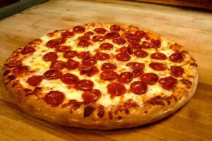 A closeup look at the Pepperoni pizza kept on the wooden table.