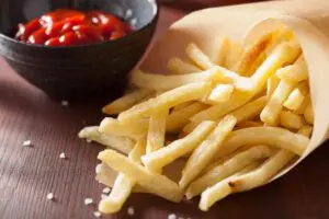 French fries in a paper bag with ketchup.