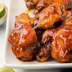 Glazed chicken wings on a white plate.